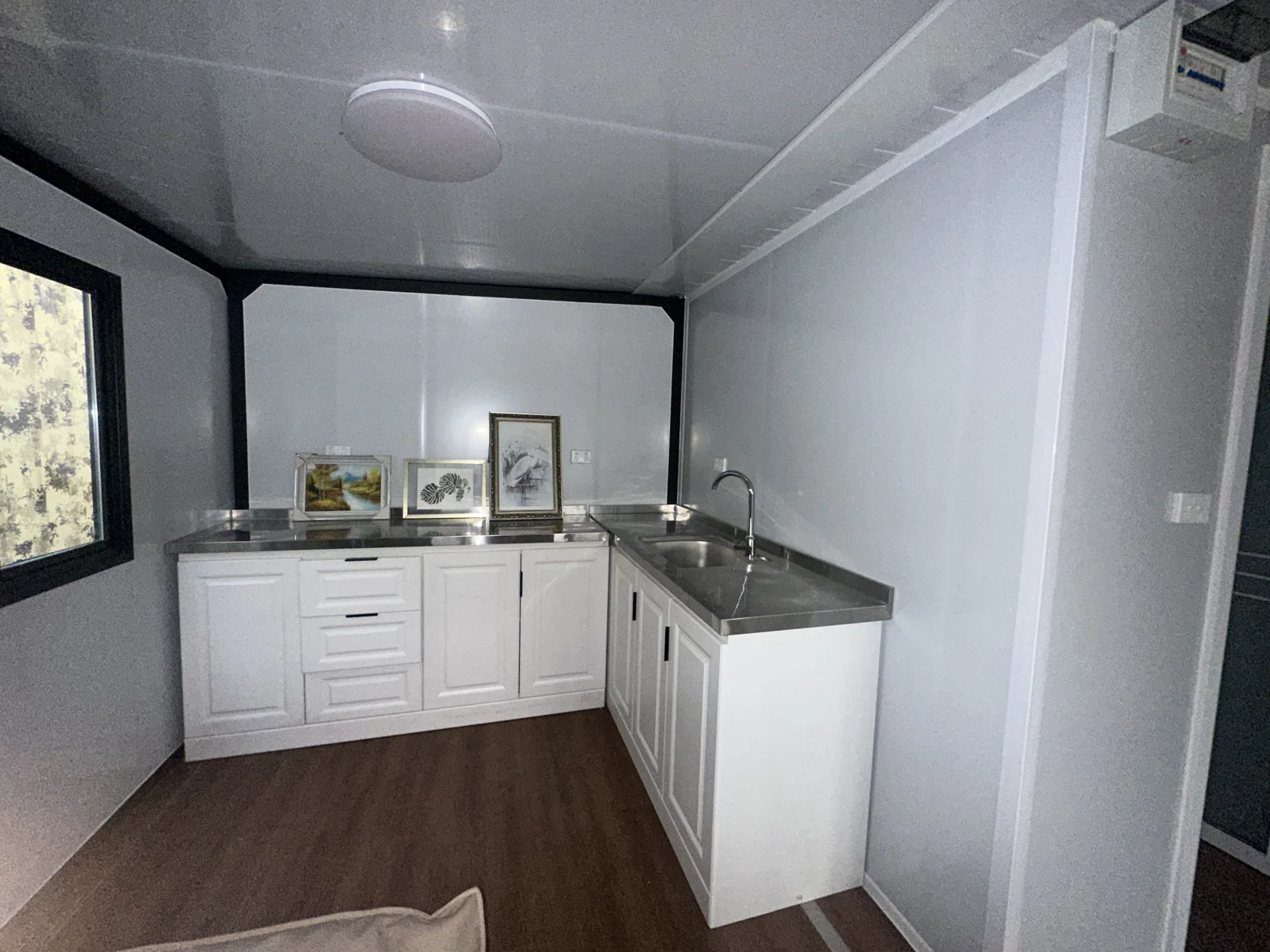 Interior of a HUAYING expandable container house showing sealed window frame and serviceable wall lining
